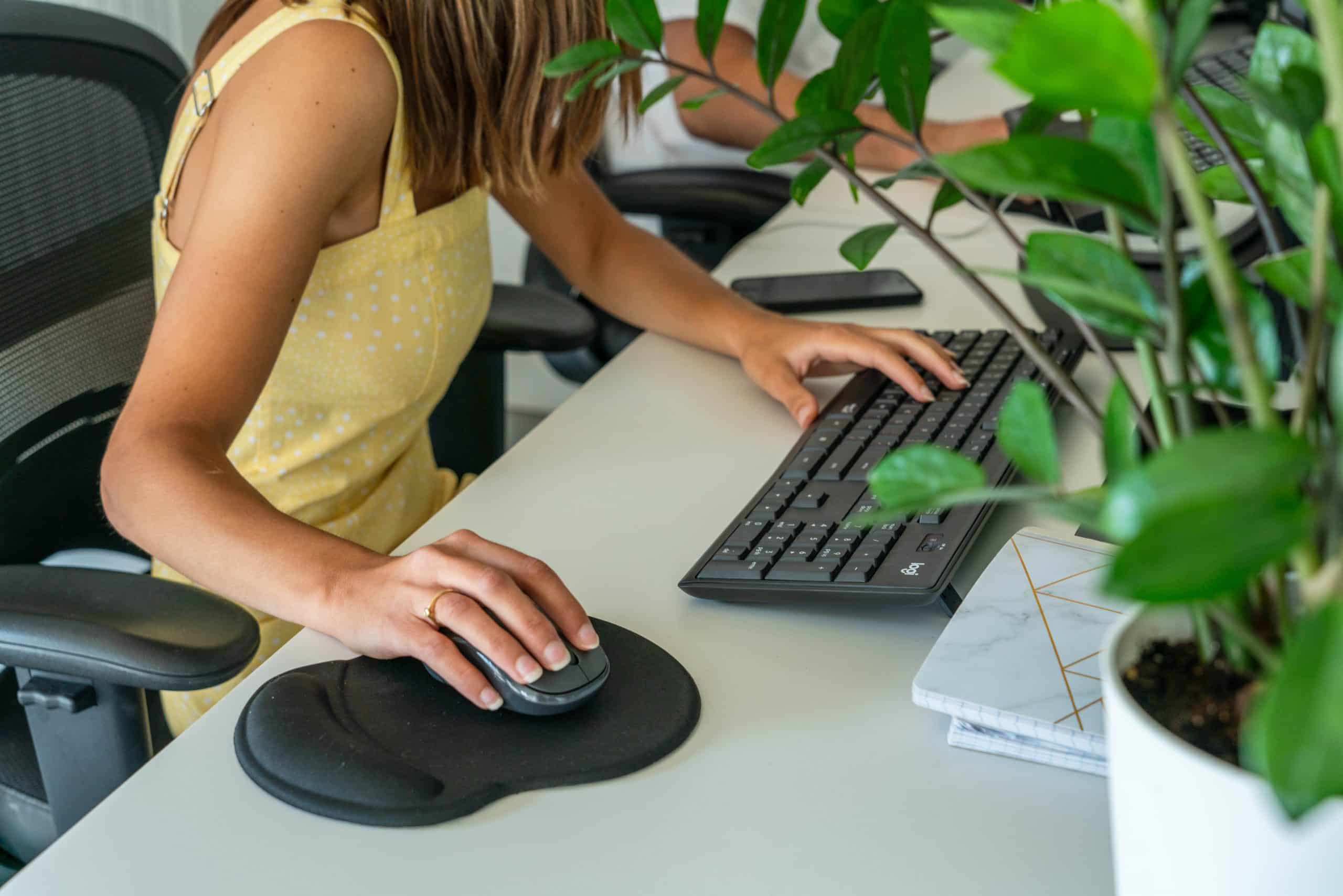 Une jeune femme travaille à son ordinateur derrière son bureau.